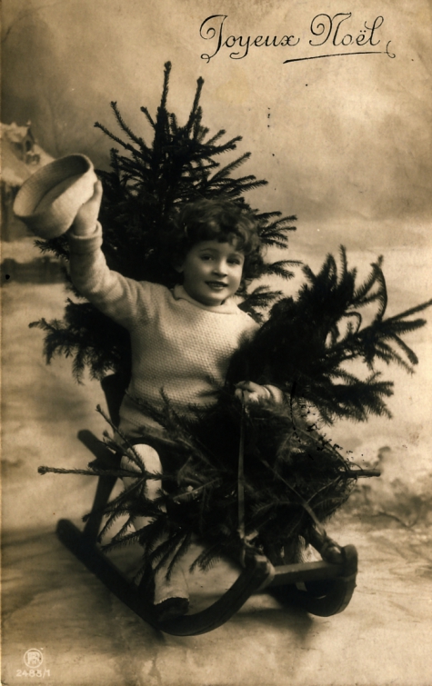 Beeldzijde kerstkaart, kindje op slede met sparren, 1910